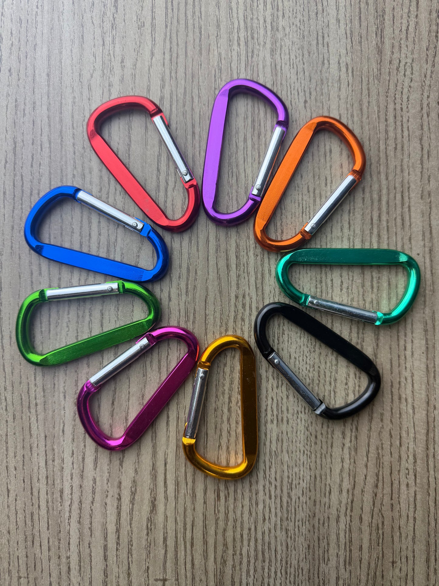 Colorful carabiners arranged in a circle on a wooden surface